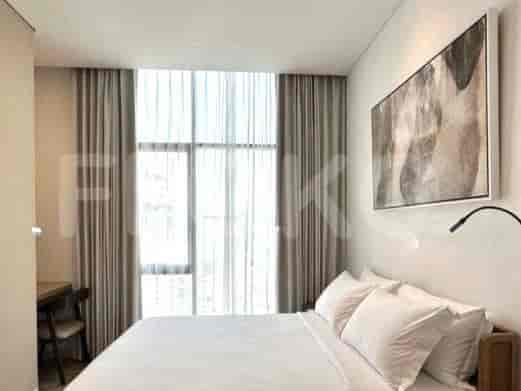Bedroom with bed, large window, and curtains.