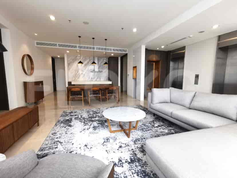 Modern living room with a grey sectional sofa, dining area, and marble accents.