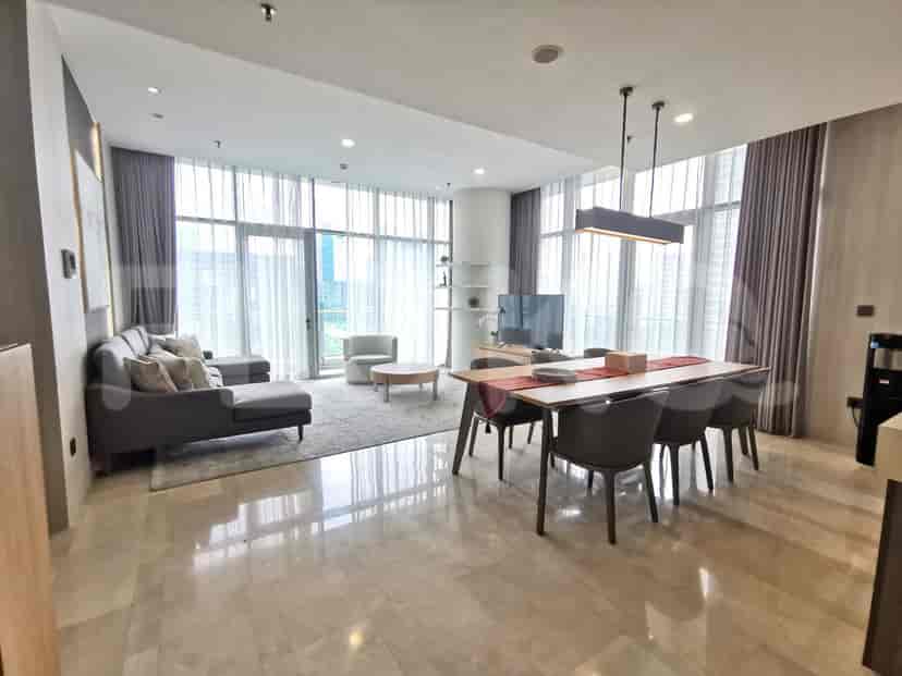 Well-lit living room with floor-to-ceiling windows, grey sofa, and round coffee table.