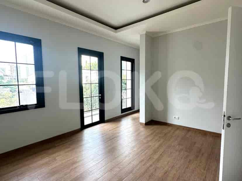 Another bedroom with light wooden flooring and multiple windows.