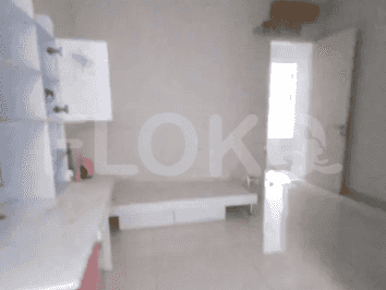 Kamar tidur cerah dengan dinding putih, meja, dan lemari kecil.