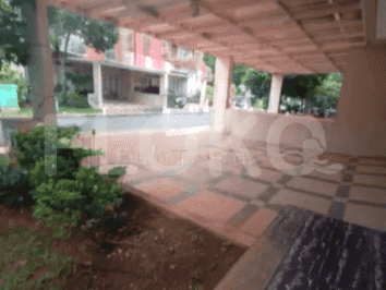 Pemandangan dari jalan masuk, menampilkan area parkir beraspal dan pintu masuk depan rumah.