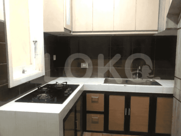 Tampilan dekat dapur dengan backsplash hitam, kompor gas, dan lemari kayu.