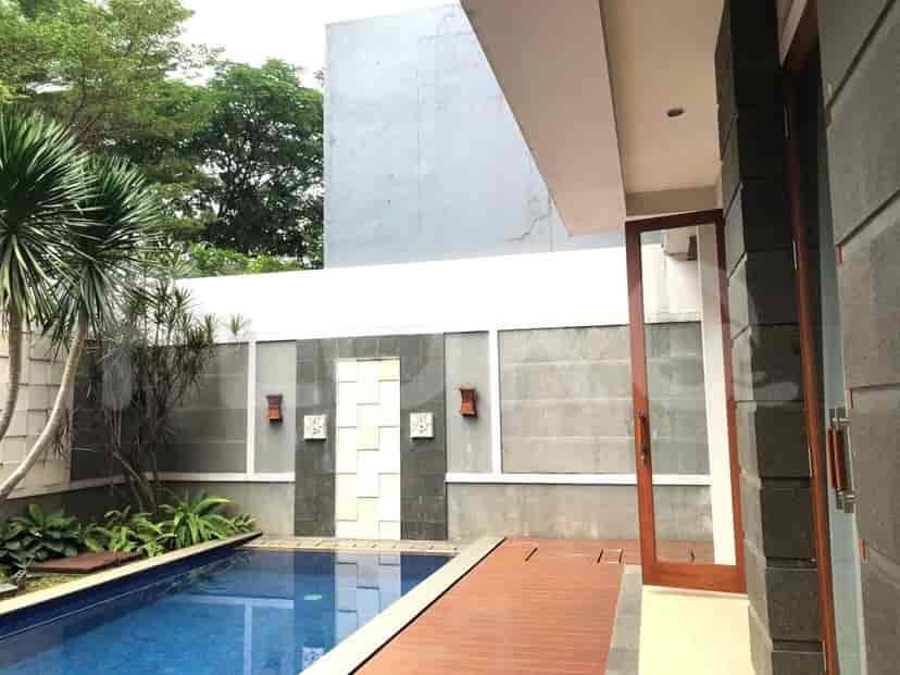 Tampak luar dari sebuah vila modern dengan kolam renang, dek kayu, dan tanaman hijau yang subur.