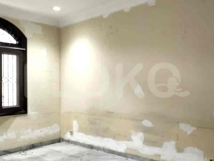 Sudut kamar tidur dengan jendela, yang menunjukkan dinding yang sebagian dicat.