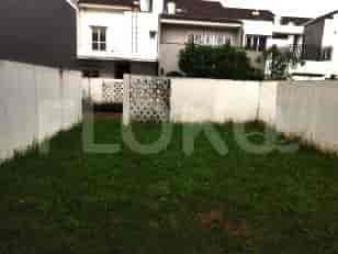 A small garden with grass, white wall, and fence.