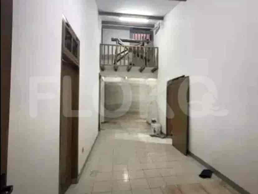 An interior hallway with tiled floor, white walls, and a staircase leading to the upper level.