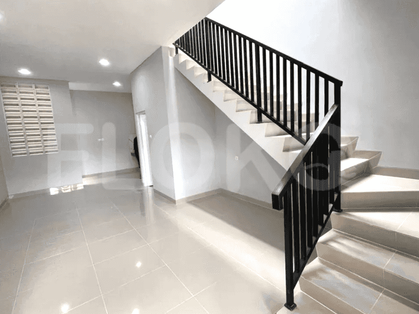 Tangga modern dengan pagar logam gelap dan lantai berubin, mengarah ke tingkat atas rumah.