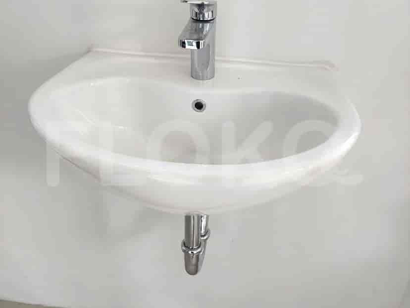 Tampak dekat wastafel putih dengan keran krom.