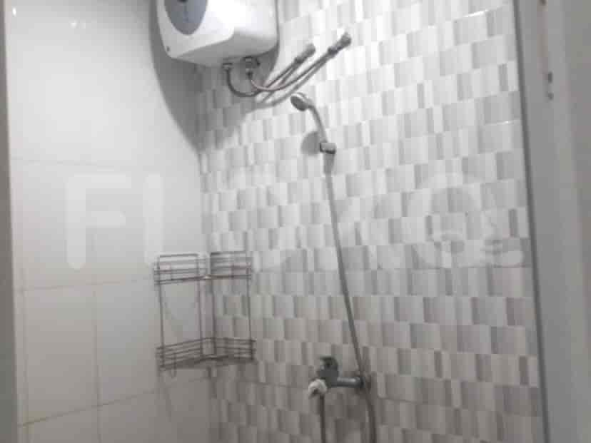 Kamar mandi dengan pancuran hujan, pemanas air, dan ubin abu-abu.