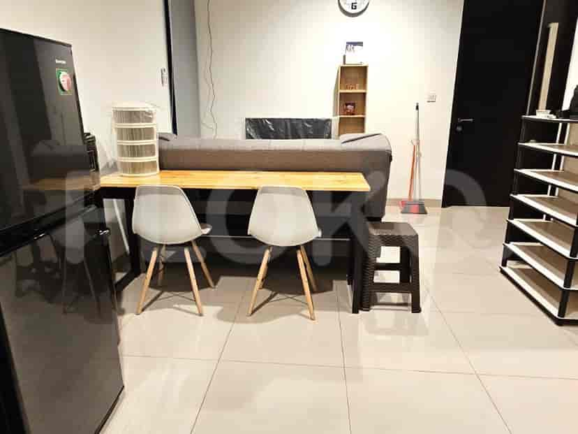 Ruang tamu dengan meja dan kursi di samping sofa dan lemari es.