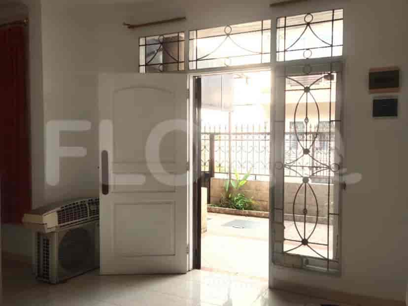 Lobi pintu masuk dengan pintu putih, jendela di sebelahnya dengan jeruji besi dekoratif, dan unit penyejuk udara.
