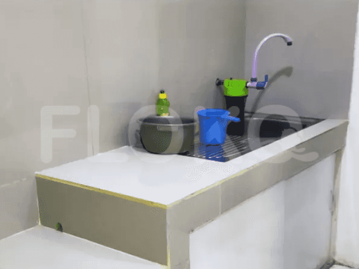 Meja dapur dengan wastafel dan keran, dengan beberapa perlengkapan pembersih.