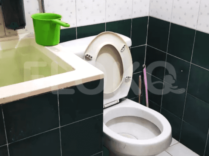 Kamar mandi dengan toilet, wastafel dengan aksesoris hijau.