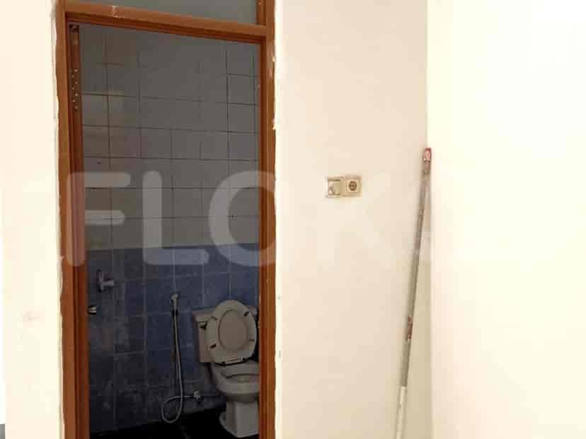 Kamar mandi dengan ubin biru, toilet, dan kusen pintu.