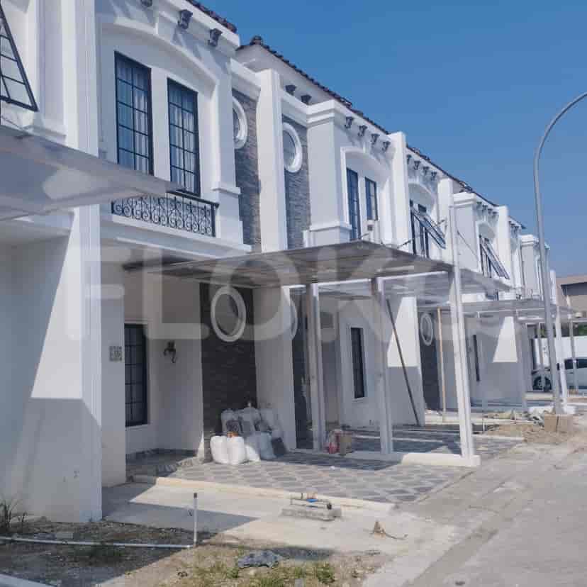 Tangga yang cerah dengan dinding putih, lantai ubin berwarna terang, dan pagar logam dekoratif.