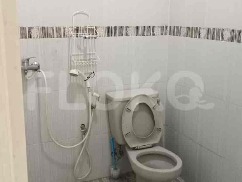 A bathroom with a toilet, shower, and a shelf.