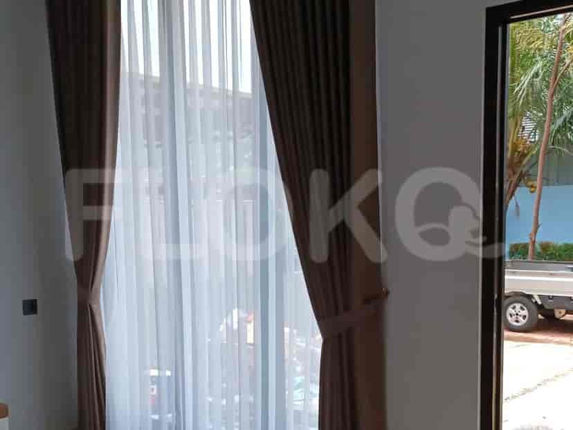 A well-lit room with sheer curtains and brown curtains.