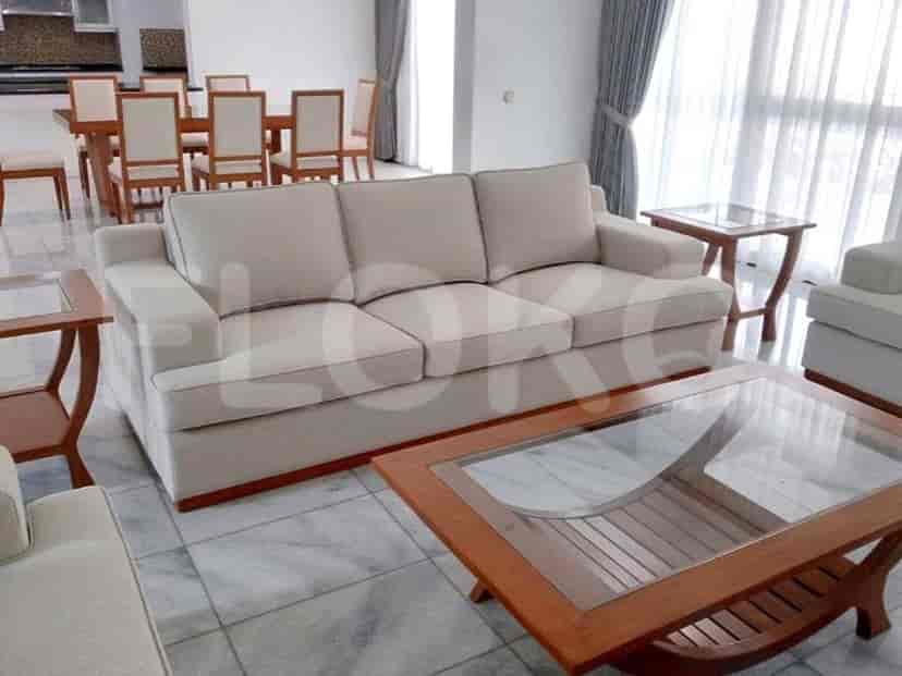 A spacious living room with cream-colored couches, wooden tables, and tiled flooring.