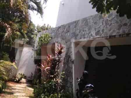 Exterior view of the property with a stone facade, garage, and lush greenery.