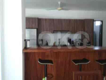 A modern kitchen with a wooden bar, stainless steel refrigerator, and wooden cabinets.