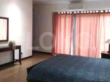 A bedroom with a large bed, a desk, and a mirror.