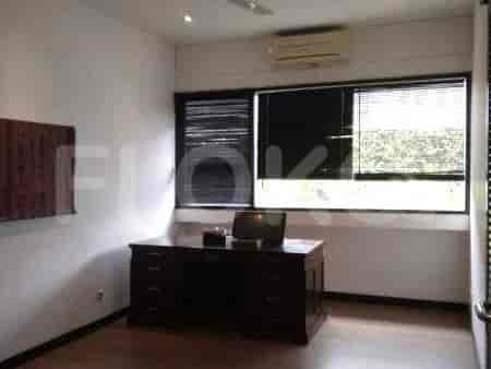 A home office with a large wooden desk, a window with blinds, and an air conditioning unit.