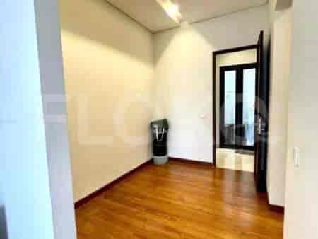 A small entryway with light wooden flooring, white walls, and a black trash bin.