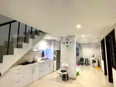 A bright kitchen with white cabinets, a stainless steel refrigerator, and a dining area with a large wooden table and chairs.