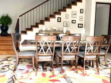 A dining room with a large wooden table and chairs.