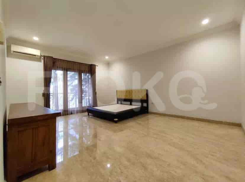 A spacious master bedroom with a bed, a wooden dresser, and a large window.