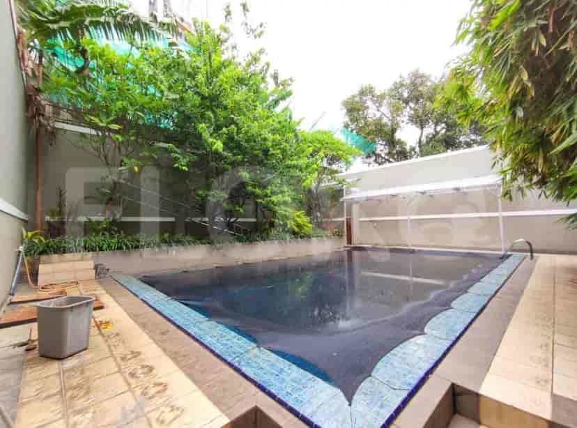An outdoor swimming pool with a patio, surrounded by trees.