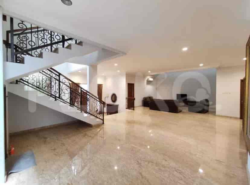A spacious living room with marble flooring, a staircase with a wrought-iron railing, and an open floor plan.
