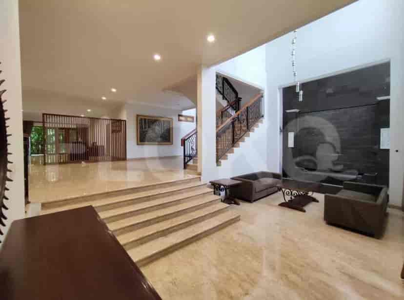 A living room with a staircase, seating area, and large windows with sheer curtains.