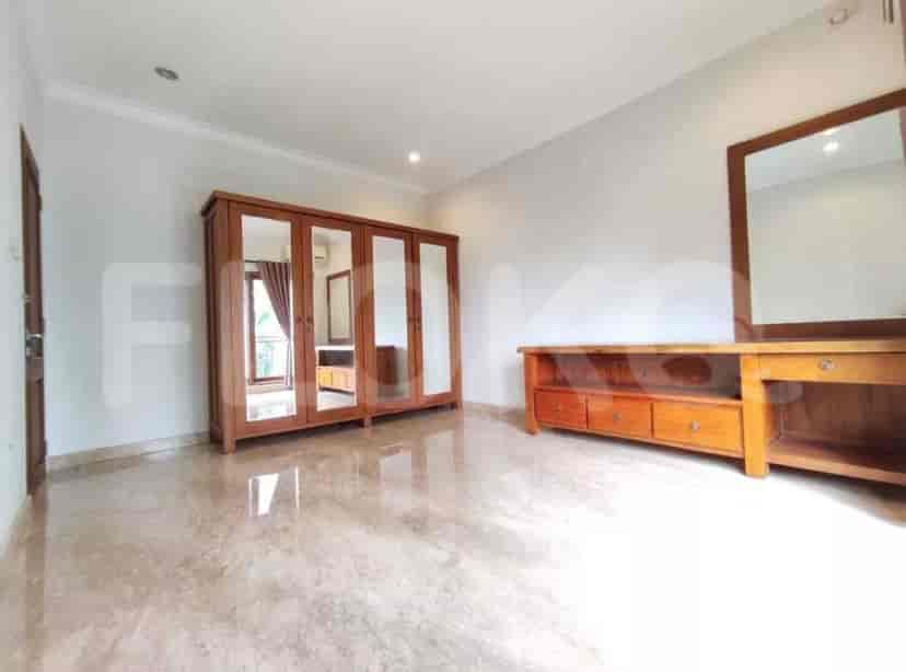 A bedroom with a large wooden wardrobe, a wooden dresser, and a mirror.