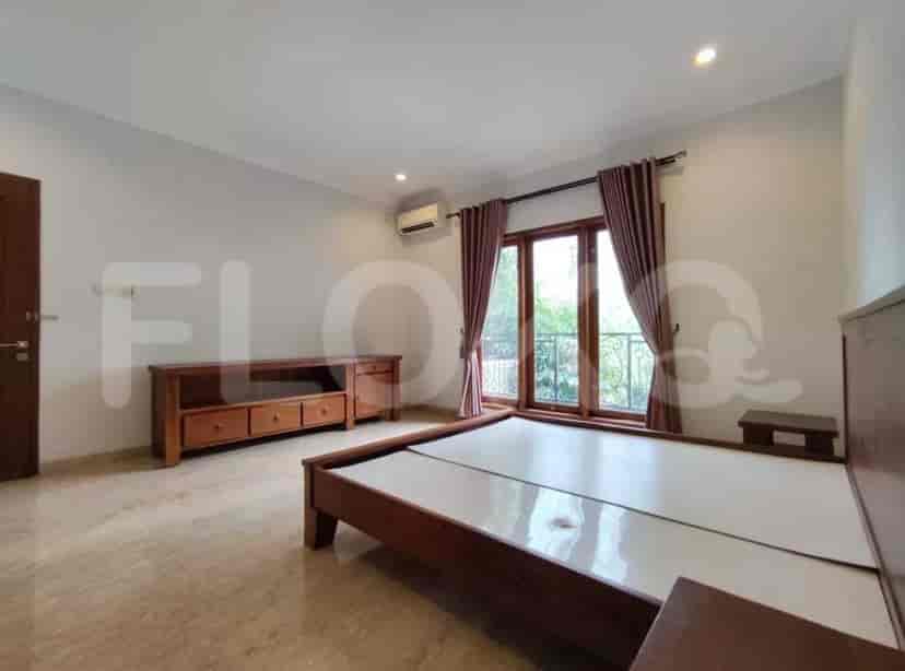 A bedroom with a bed, wooden furniture, air conditioning, and a view through a window.
