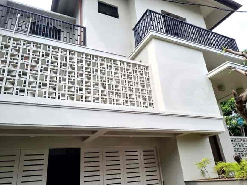 A modern, two-story house with a distinctive facade featuring a decorative concrete screen and black metal balconies.