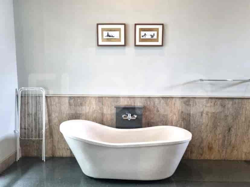 A spacious bathroom featuring a standalone bathtub, two framed pictures, and a towel rack.