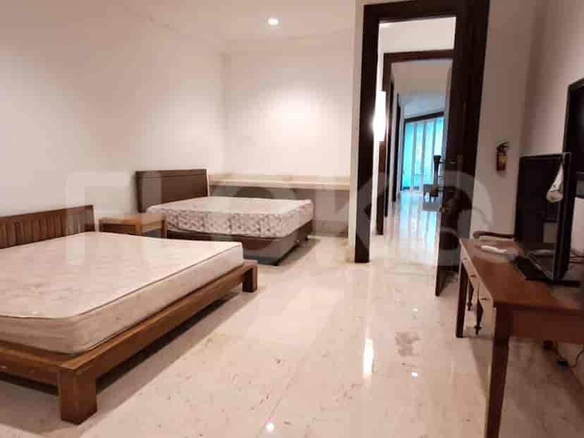 A bedroom with two beds and a view of a hallway.