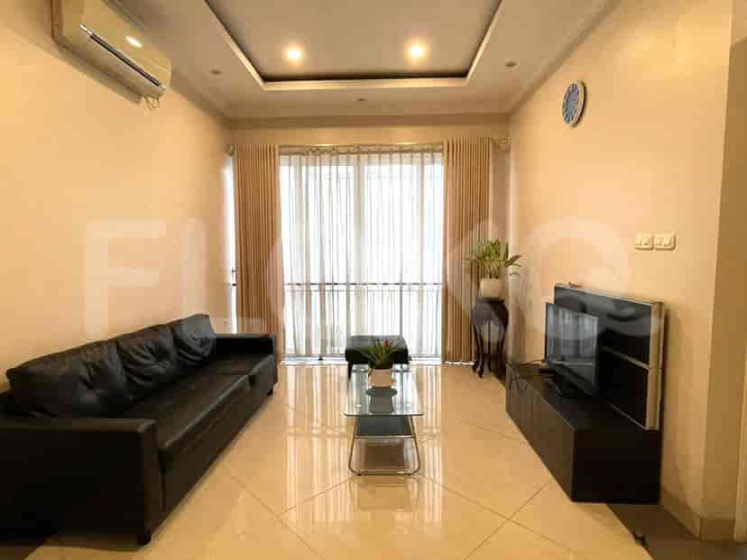 A living room featuring a black leather sofa, glass coffee table, and a dark TV console.