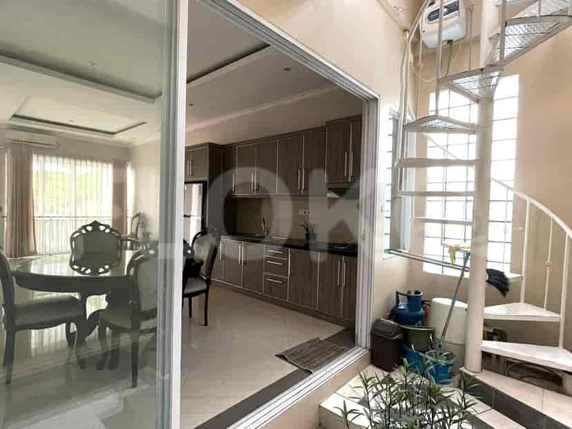 Modern kitchen with wooden cabinets, integrated appliances, and a spiral staircase leading upstairs.