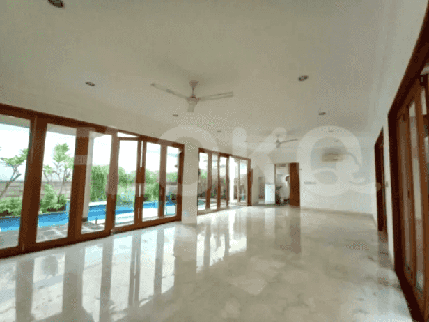 A spacious living room with large windows, ceiling fans, and access to the swimming pool.