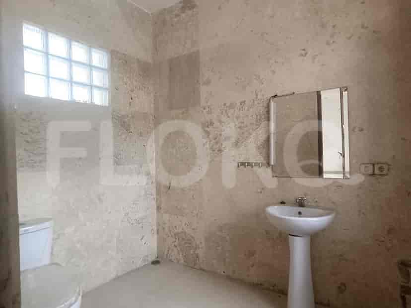 A bathroom with light colored stone walls, a sink, and a mirror.