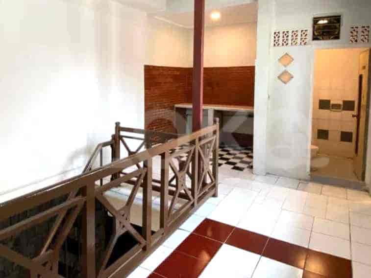 The corridor showing a staircase and a view into a kitchen with checkerboard tiling.