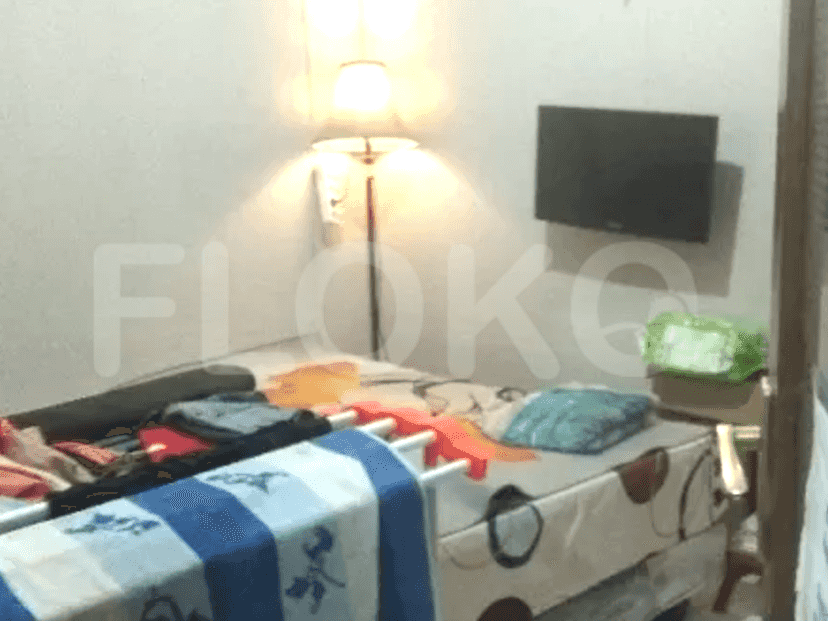 A bedroom with a bed, lamp, and a small wall-mounted TV.