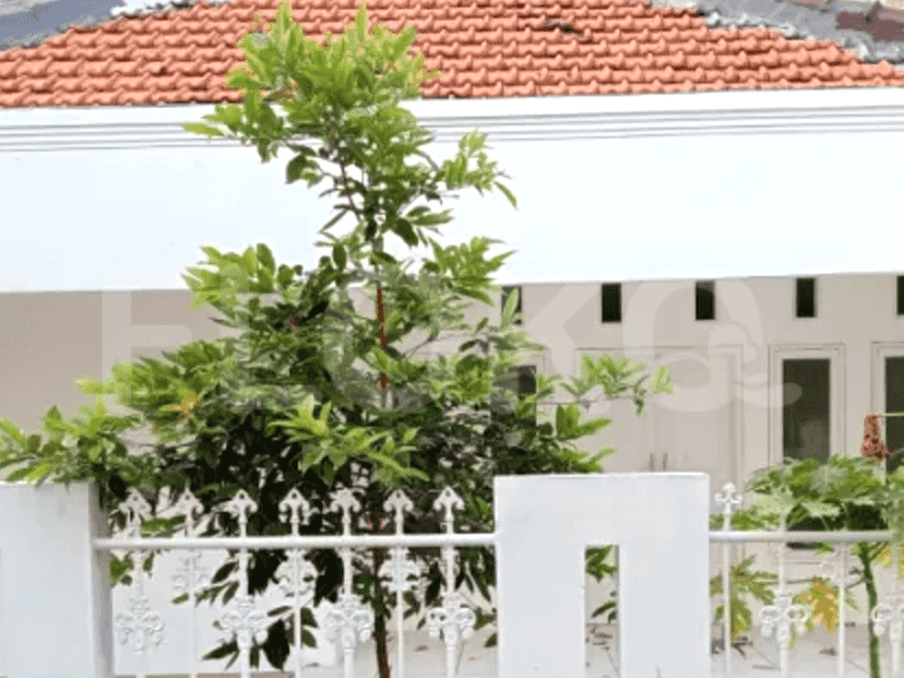A house with white walls, a red tiled roof, and a decorative white fence.