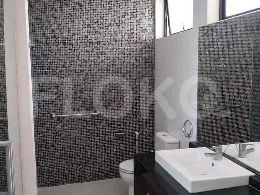 A bathroom with a glass shower enclosure, a toilet, and a vanity with a black countertop.