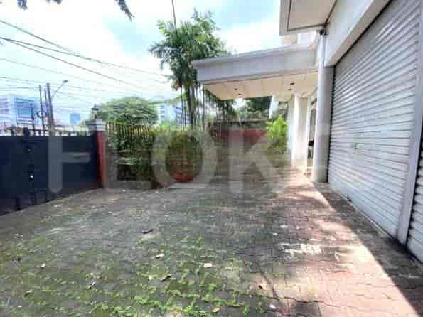Eksterior rumah dengan jalan masuk, gerbang, dan area teras tertutup.