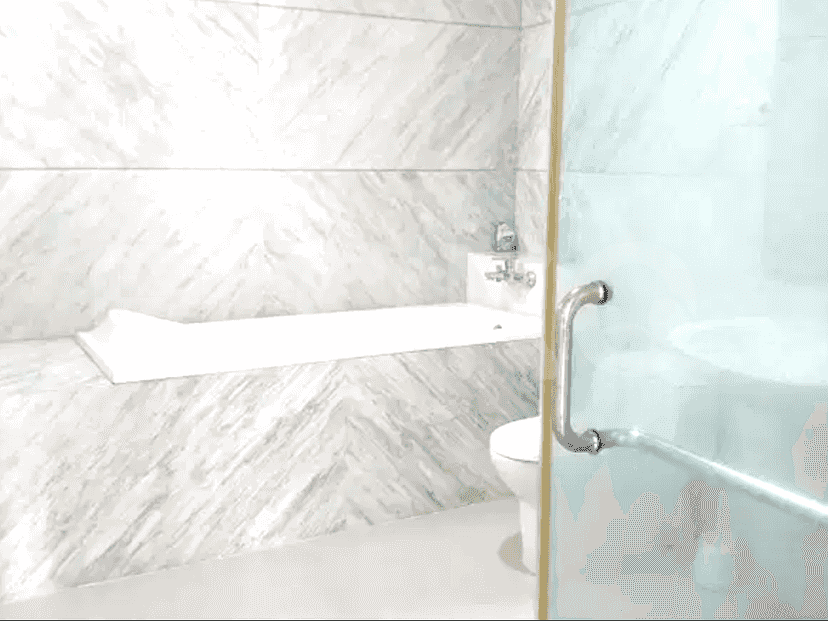 Kamar mandi yang menampilkan bak mandi built-in, bilik pancuran kaca, dan dinding marmer.
