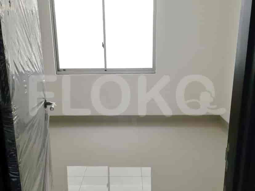Pemandangan ke kamar tidur kosong dengan jendela, dinding putih, dan lantai abu-abu.